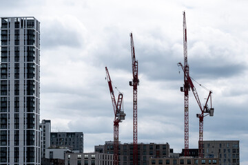 A striking city skyline dominated by multiple construction cranes, symbolizing growth and development against a dramatic cloudy sky, emphasizing urban advancement and change in London UK