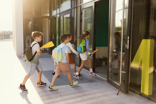 Girls and boys with backpacks entering school