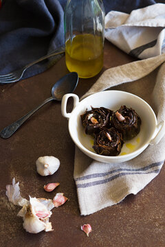 Baked artichokes in stew spot with garlic on table