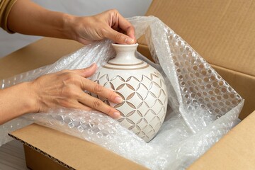 Hand pack ceramic vase with bubble wrap. Shipping protection