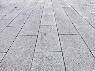 A clean, gray concrete surface featuring rectangular tiles arranged in a neat pattern under bright daylight