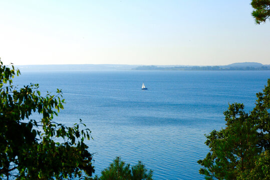View of a lake from the Gnitz Peninsula in Usedom, Mecklenburg-Vorpommern, Germany, with a sailboat on the water.