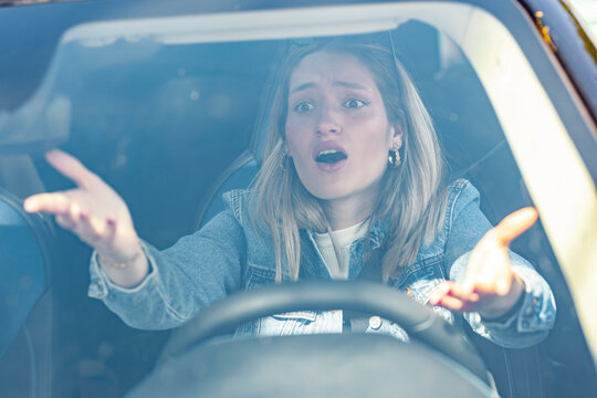 Frustrated woman gesturing in car during daytime