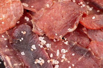 dried dried meat from meat tenderloin with spices and salt on black slate