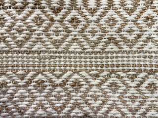 Close up of hand made flat weave rug texture in white and pale brown color. Vintage carpet concept hand sewn weaving diamond shape pattern seamless background.