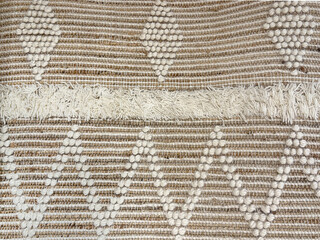 Close up of hand made flat weave rug texture in white and pale brown color. Carpet rug texture of vintage hand sewn weaving diamond and zig zag pattern seamless background.