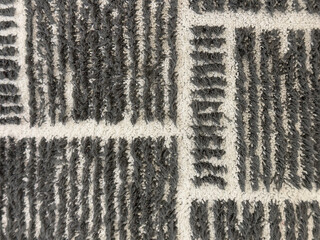 Close up of carpet floor texture in black and white stripes pattern. Monochrome carpet rug black and white horizontal and vertical stripes seamless background texture.