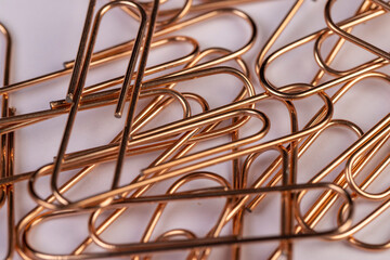 large-sized copper paper clips lie on white blank paper