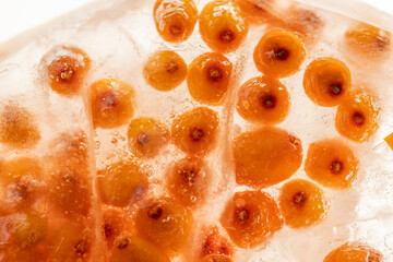 ripe orange sea buckthorn berries frozen in water