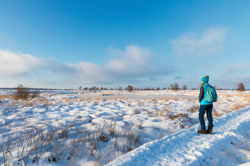 Woman hiking on a snowy boardwalk in High Fens Nature Park