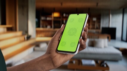 GREEN SCREEN CHROMA KEY A modern indoor living room setting during the day, with a person holding a phone. Ideal for apps showcasing home or tech-related features