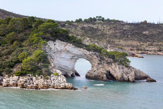Scenic view of Torre di San Felice near Vieste, Italy with a natural rock arch and coastline