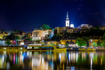 Night view over the Sava River to New Belgrade with illuminated architecture and boats.