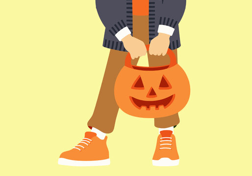 A child holding a jack-o'-lantern bucket in casual clothing