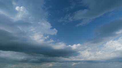 Summer skyscape with dark storm rain clouds on sky. Clouds against a blue sky turning into dark rain cyclones. Timelapse.