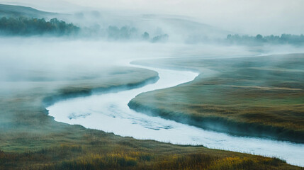 Sunlight breaking through foggy fields with a river winding through.