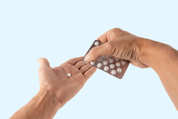 Male hands getting a pill from a medicine blister isolated on cyan background