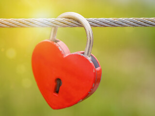 Lock of love and heart. Close-up of love lock in shape of red heart with soft focus on green...