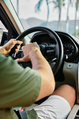 Man driving a car with hands on the steering wheel, dashboard visible in the background