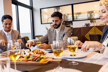 Smiling coworkers in restaurant talking during business lunch.