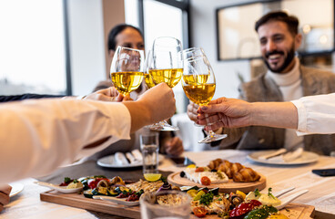 Close up of coworkers in restaurant toasting with wine during business lunch.