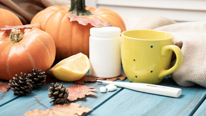 Autumn cold, Tea with lemon, thermometer, ginger, pumpkin, tablets and dry leaves on a black background. top view, flat lay