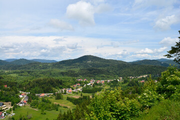 Fototapeta premium A view towards the municipality of Lokve as seen from a lookout point on the road above Lokve Lake (Lokvarsko jezero) in Croatia, featuring lush forests and picturesque village scenery