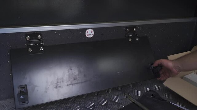 A person reveals the storage compartment designed for the spare tire of a minivan. The compartment is conveniently located, demonstrating practical vehicle features essential for road trips.
