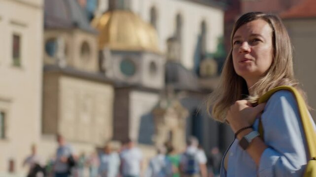 Woman carrying yellow backpack walking in Krakow, Poland. Female tourist exploring European city streets in summer day
