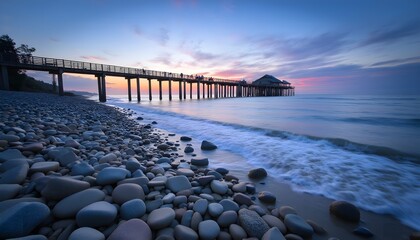 Obraz premium Calm beach at dusk with rocky shoreline and wooden pier in the background