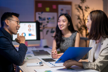 Three people are sitting at a table with a blue folder in front of them