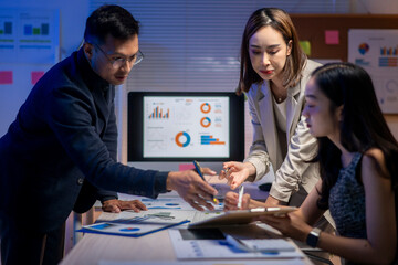 Three people are sitting at a table with a computer monitor in front of them