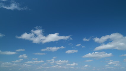 Obraz premium Wispy cumulus and stratocumulus clouds pass over blue sky in nature. Elongated cumulus clouds move across sky. Timelapse.