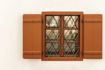 A charming window adorned with wooden shutters set against a white wall