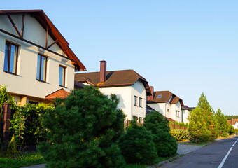 Street in residential area in suburb. Rows of houses along road, sidewalk. Family house outside city. Dream country home. Home outside the city. Road at village. Trees and green lawn at Villa.