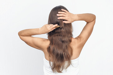 Rear view of lady combing natural long hair with wooden comb on white background, isolated. Hair care.