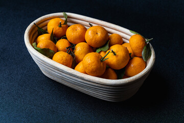 pile of mandarin orange on a wooden bucket, dark background