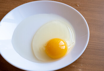 A raw egg in a white dish photographed from above.