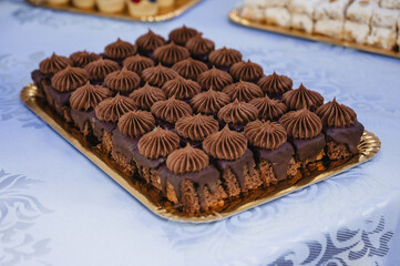 A rectangular tray filled with chocolate-covered desserts. These desserts have a rich chocolate base and are topped with a swirl of creamy chocolate frosting.