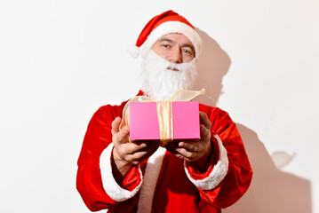 Man in costume of Santa Claus holds present box on white background, Christmas and New Year time. 