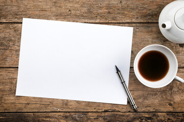 Rustic wooden table background with teapot and tea cup, copy space on blank paper