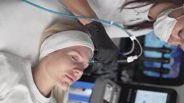 Woman doing HydraFacial Vacuum Facial Hydropeeling Procedure in Beauty Salon,
