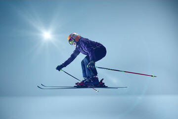 Side view of athlete executing precise ski jump, wearing purple jacket and mirrored goggles against...