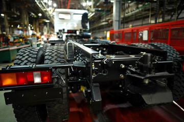 Fototapeta premium Truck production line. Assembly line. Engine install on frame of Wheel chassis of Heavy duty truck plant. Workshop production of Heavy duty trucks. Trucks Manufacture. Assembly line of truck factory.