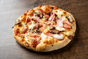 Delicious freshly baked pizza topped with ham, mushrooms, and red onions, served on a rustic wooden table. Perfect for food lovers and pizza enthusiasts. Ideal for culinary content.