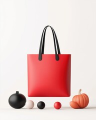 Bold red tote bag amidst minimalist autumn-themed d&eacute;cor featuring black and orange spheres and a small pumpkin on a light background