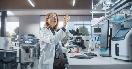 Modern Research and Development Laboratory in a Medical Center. Caucasian Female Researcher Getting Excited while Looking at Experimental Samples Inside a Petri Dish