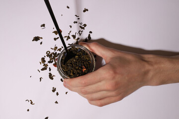 tea. dry tea leaves on a white background. hands in photo