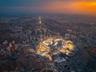 Aerial view at night of the illuminated Grand Mosque and Abraj Al-Bait Clock Tower in Mecca, showcasing the city&rsquo;s vibrant glow as lights shimmer across the holy site