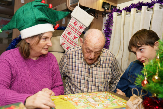 Family playing board game in decorated camper van during christmas holiday - Powered by Adobe